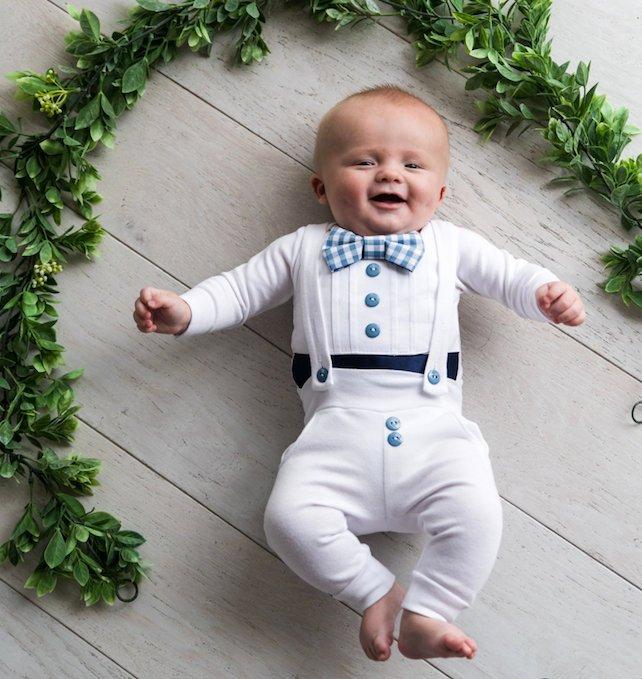 baby wearing a Bebe Couture white and blue baby boy baptism outfit with blue gingham bow tie