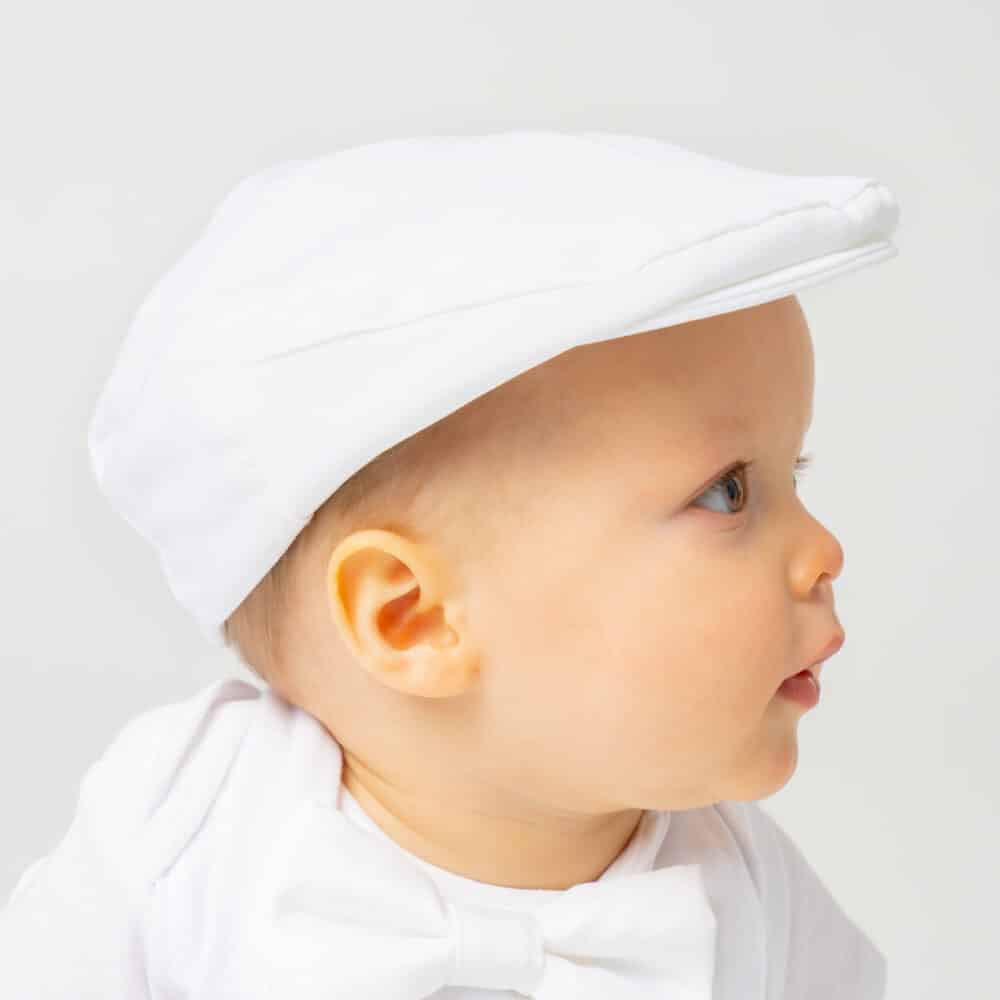 baby wearing a white newsboy cap with baptism outfit